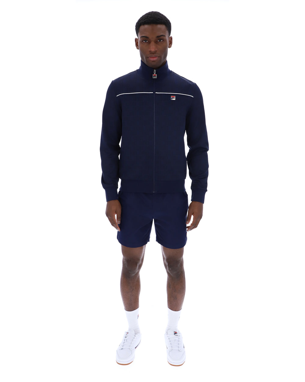Man wearing a navy tracksuit with a white logo on a white background