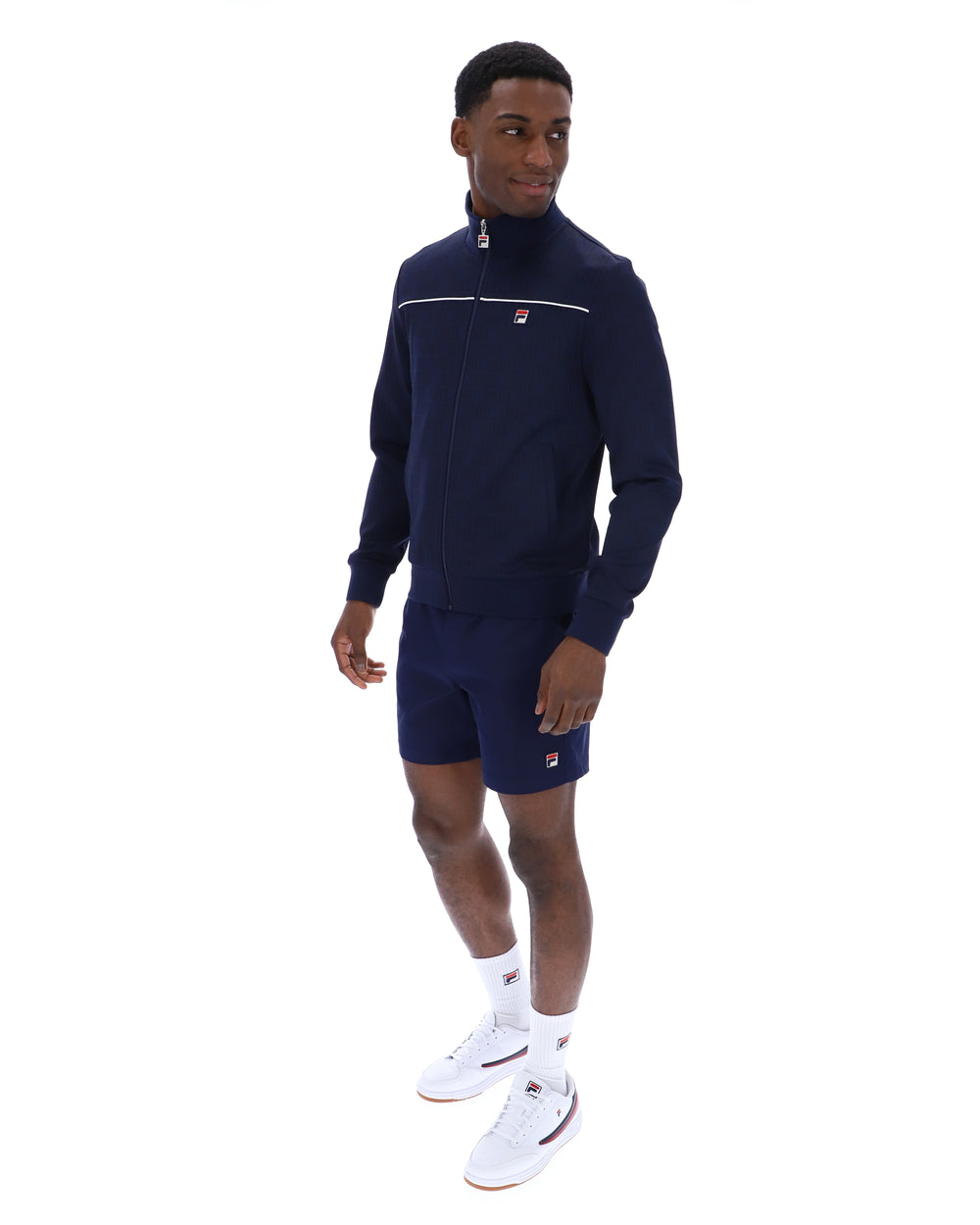 Man wearing a navy tracksuit with white accents on a white background