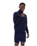 Man wearing a navy tracksuit with a white logo on a white background