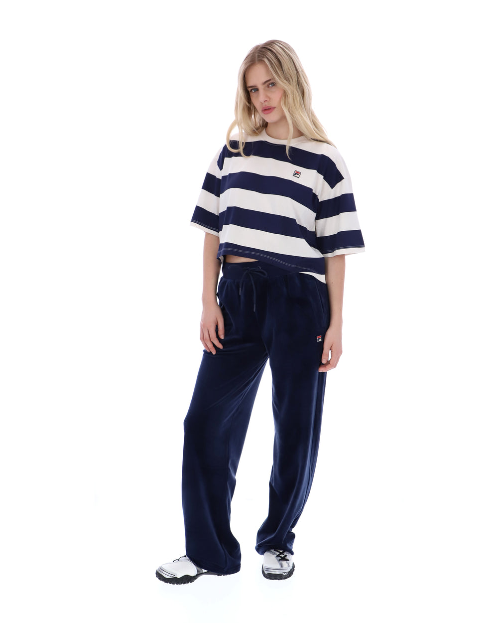 Woman wearing a striped shirt and navy pants on a white background