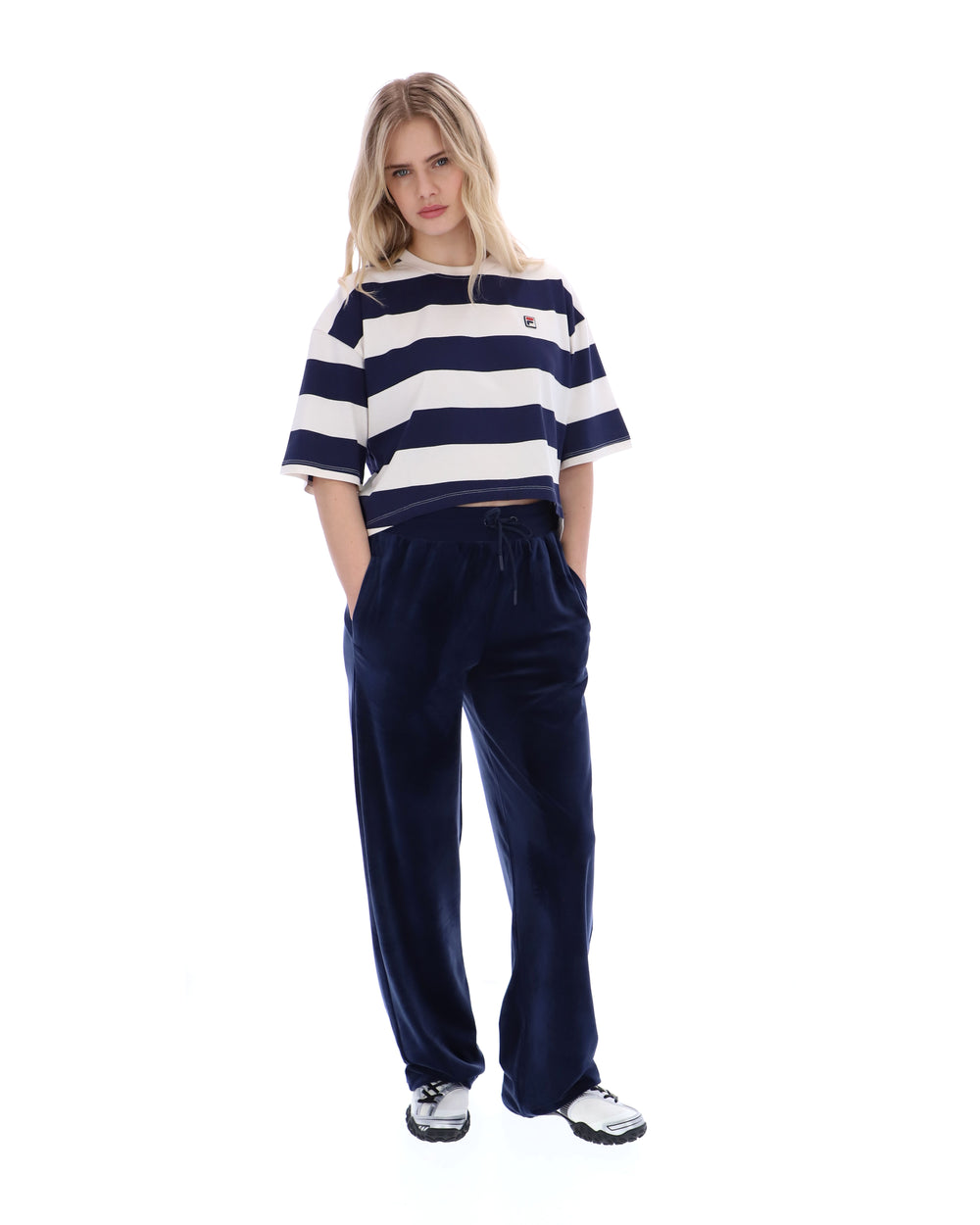 Woman wearing a striped shirt and navy velvet pants on a white background