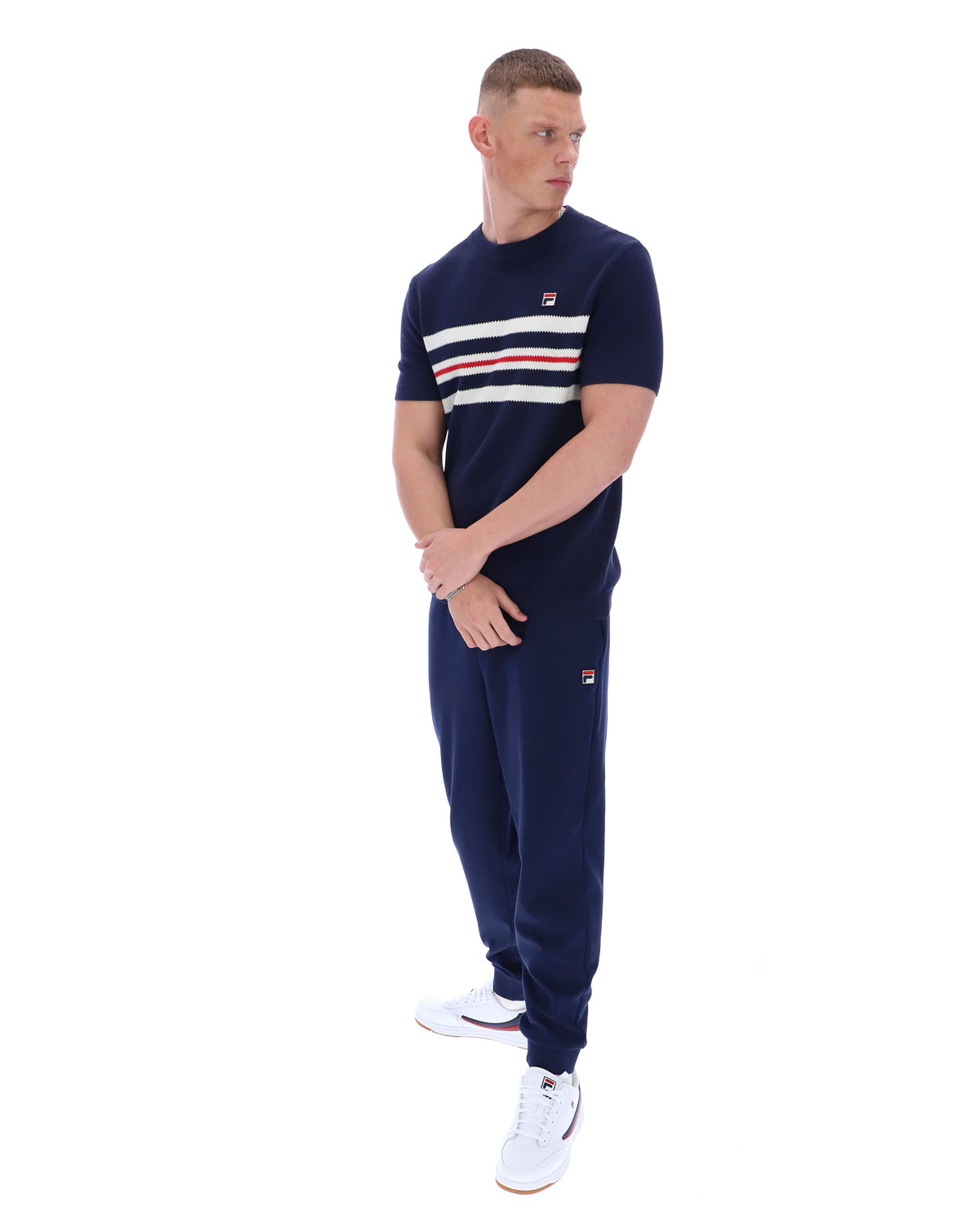 Man wearing a Navy blue t-shirt with white and red stripes and Fila logo with matching joggers on a white background