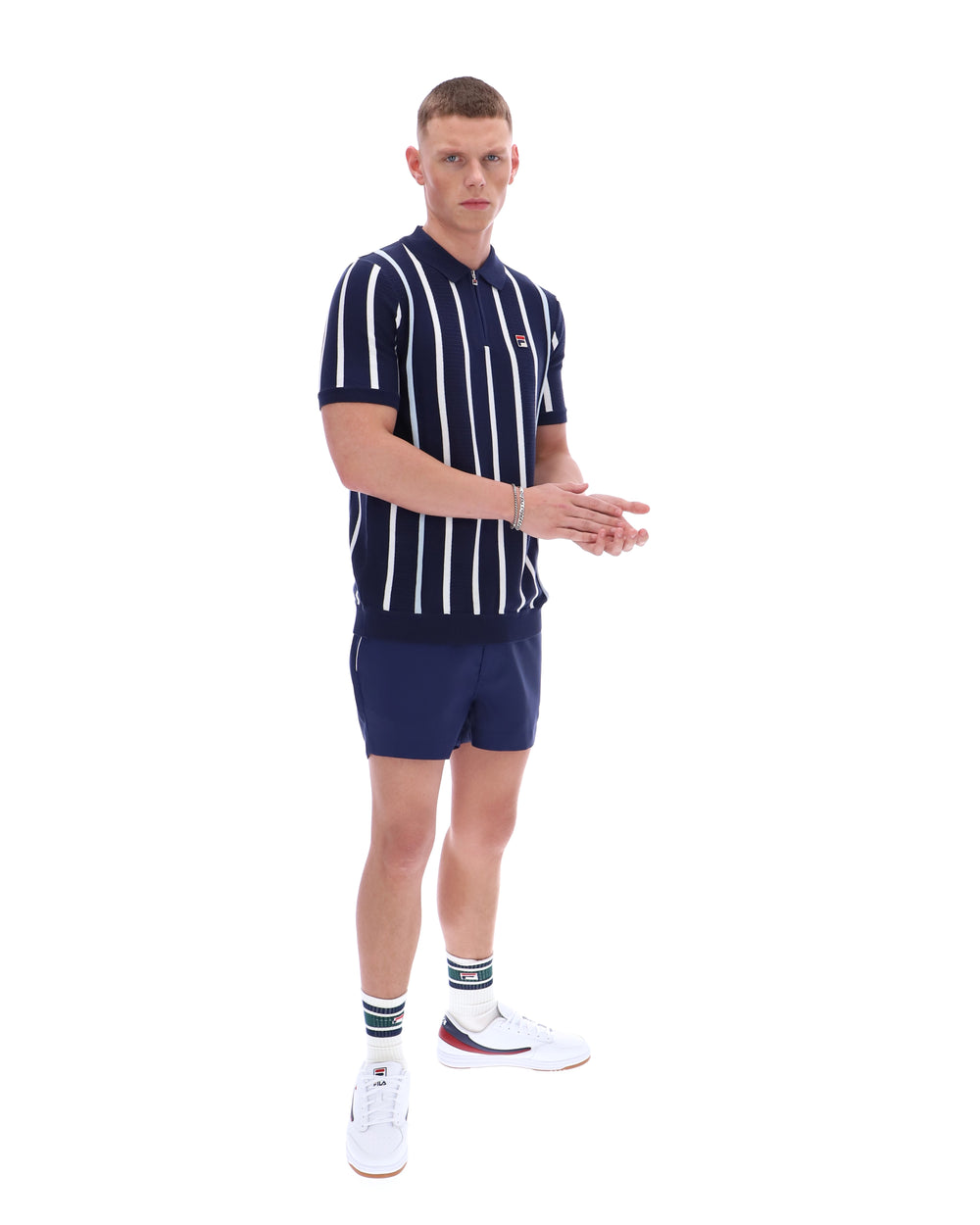 Man wearing a navy and white striped polo shirt and shorts set on a white background