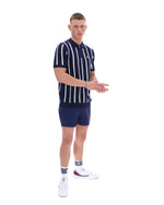 Man wearing a navy and white striped polo shirt and shorts set on a white background