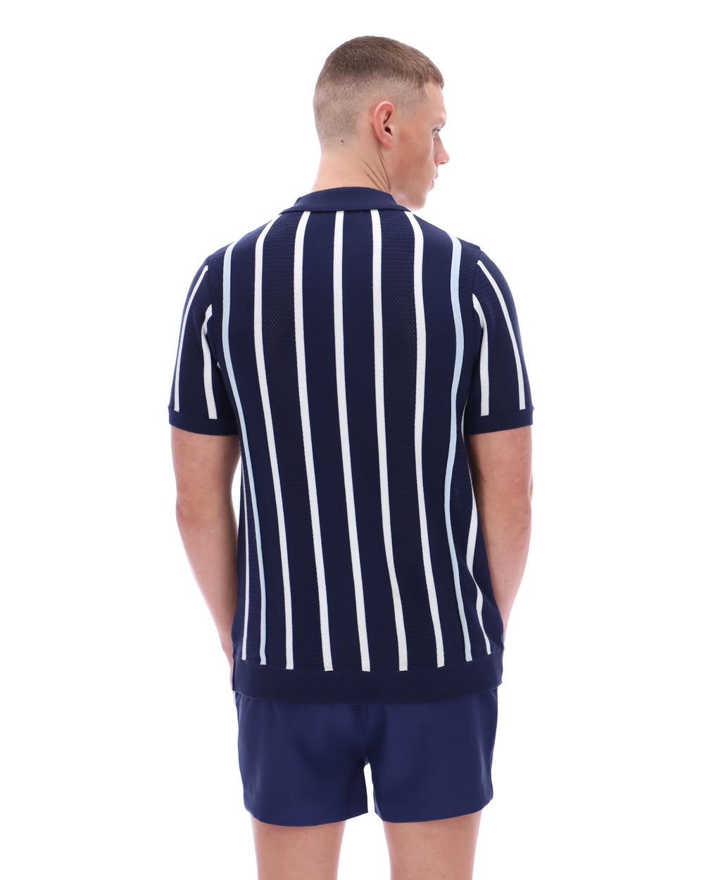 Man wearing a navy and white striped polo shirt and shorts on a white background