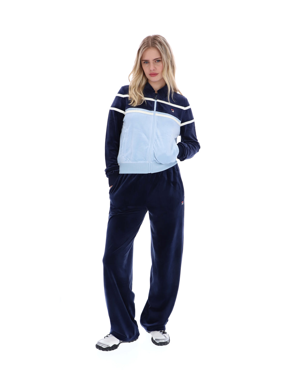 Woman wearing a navy tracksuit with a light blue panel on a white background