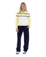 Woman wearing a yellow and white striped sweater with navy pants on a white background