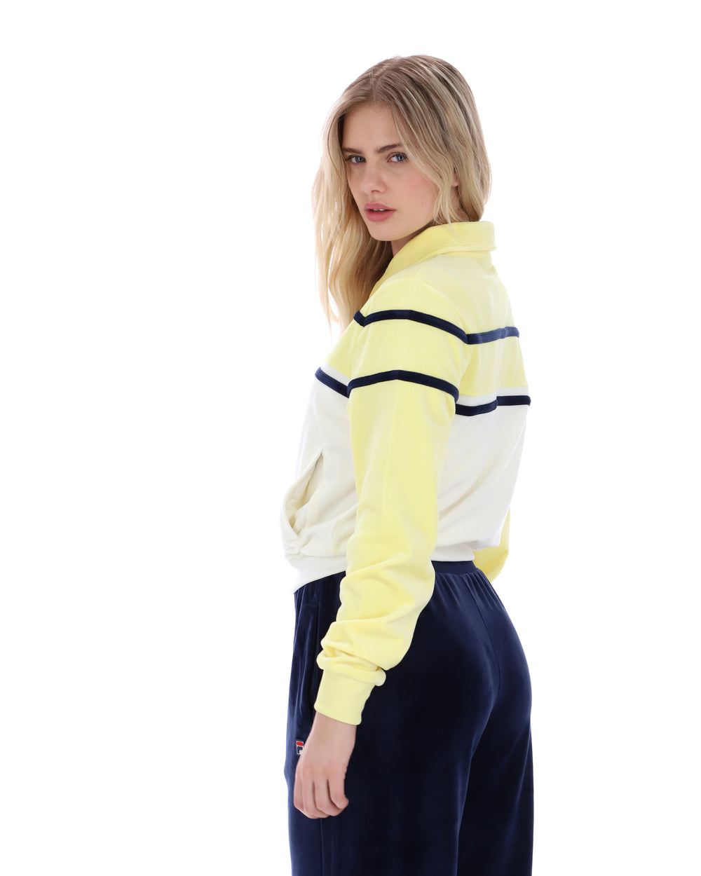Woman wearing a yellow and white striped sweater with navy pants on a white background