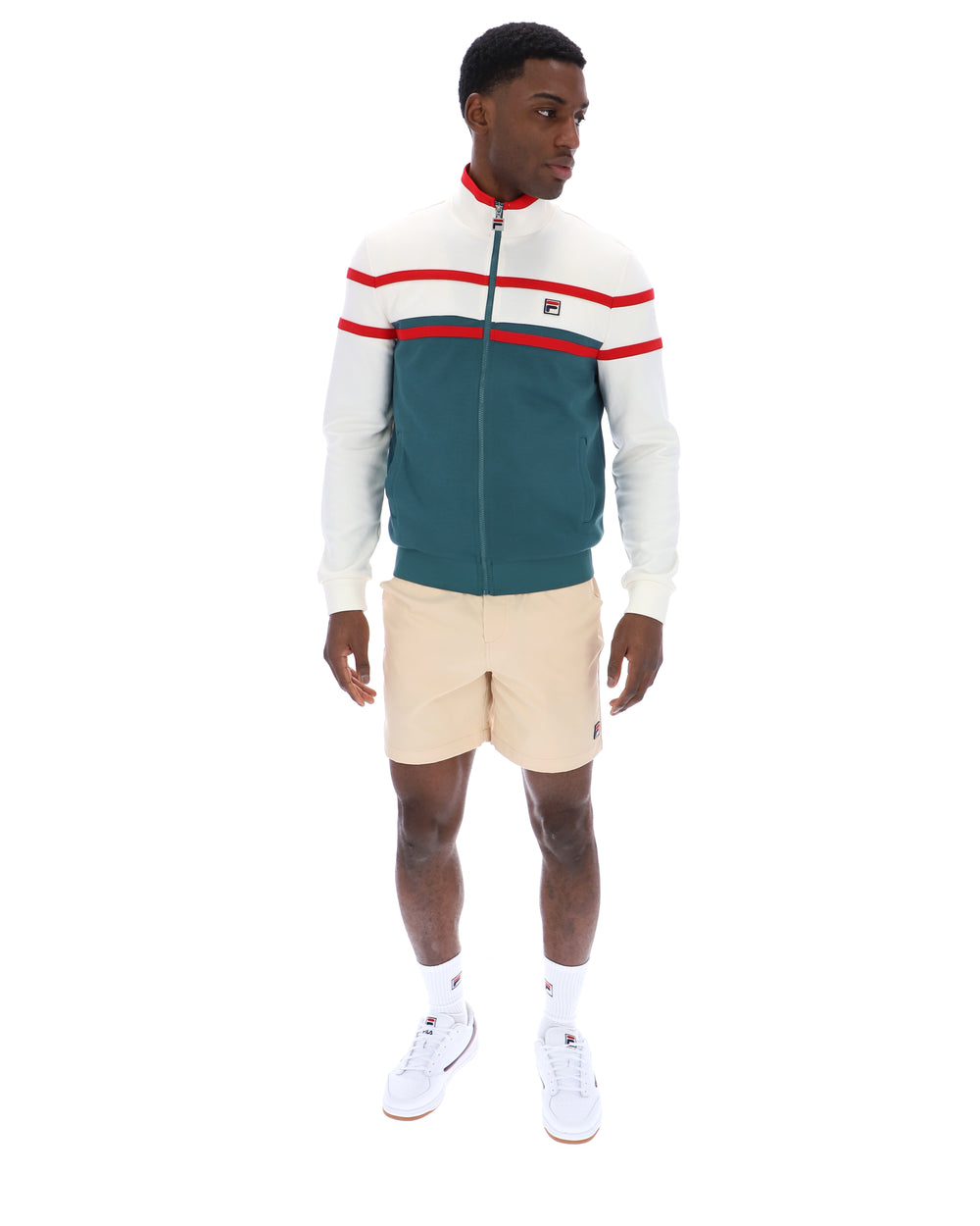 Man wearing a green and white track top with red detailing, with a FILA logo on the chest, paired with beige FILA shorts, against a white background