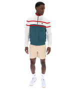 Man wearing a green and white track top with red detailing, with a FILA logo on the chest, paired with beige FILA shorts, against a white background