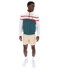 Man wearing a green and white track top with red detailing, with a FILA logo on the chest, paired with beige FILA shorts, against a white background
