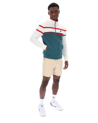 Man wearing a green and white track top with red detailing, with a FILA logo on the chest, paired with beige FILA shorts, against a white background
