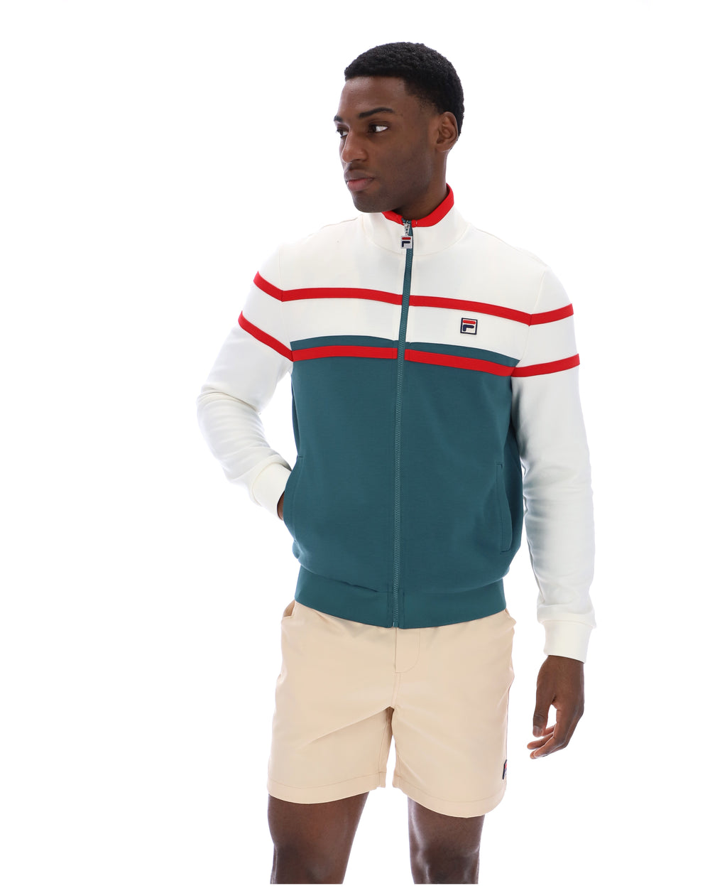 Man wearing a green and white track top with red detailing, with a FILA logo on the chest, paired with beige FILA shorts, against a white background