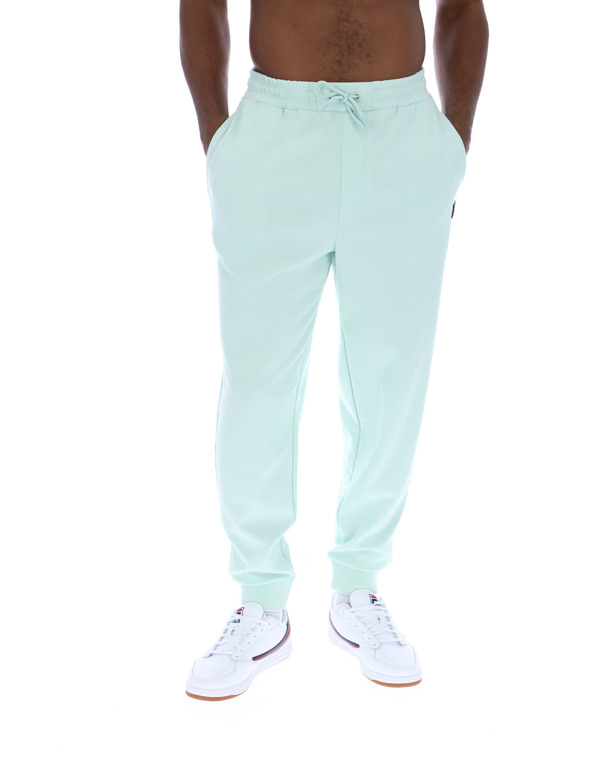 Person wearing light green sweatpants on a white background