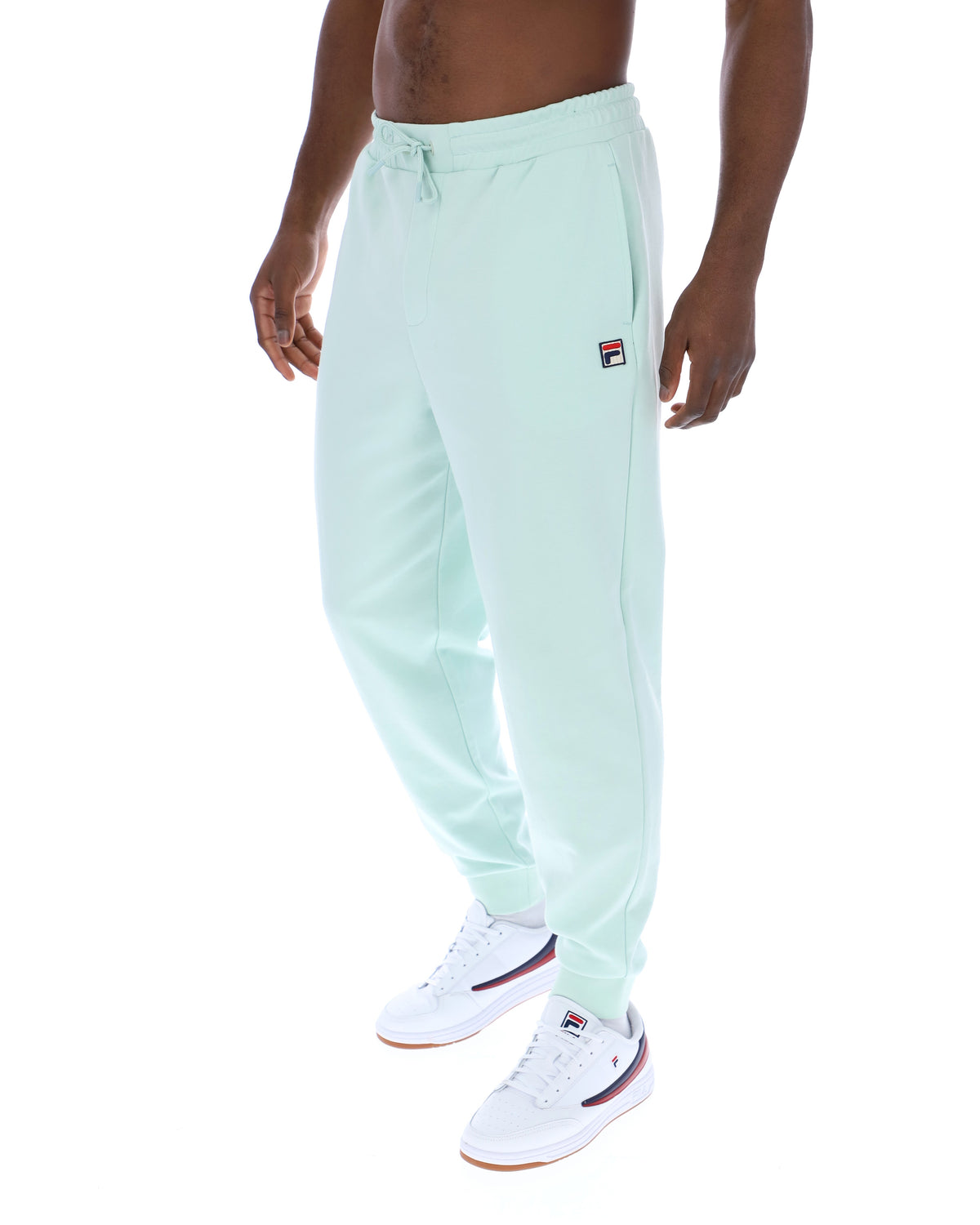 Person wearing light green jogger pants with a brand logo on a white background