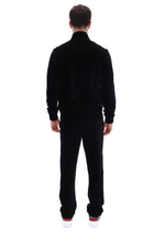 A man viewed from behind wearing a black long-sleeve mock-neck fleece jacket and matching black fleece pants, paired with white sneakers with red soles, against a solid white background.