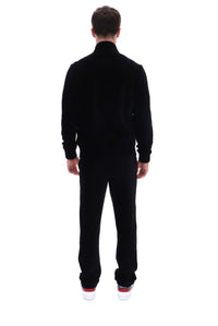 A man viewed from behind wearing a black long-sleeve mock-neck fleece jacket and matching black fleece pants, paired with white sneakers with red soles, against a solid white background.