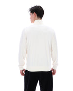 Person wearing a white sweater and black pants on a white background