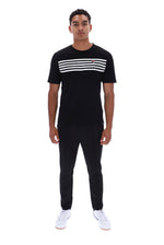 A man modeling a black short-sleeve t-shirt with three horizontal white stripes across the chest, paired with black pants and white sneakers, against a plain white background.