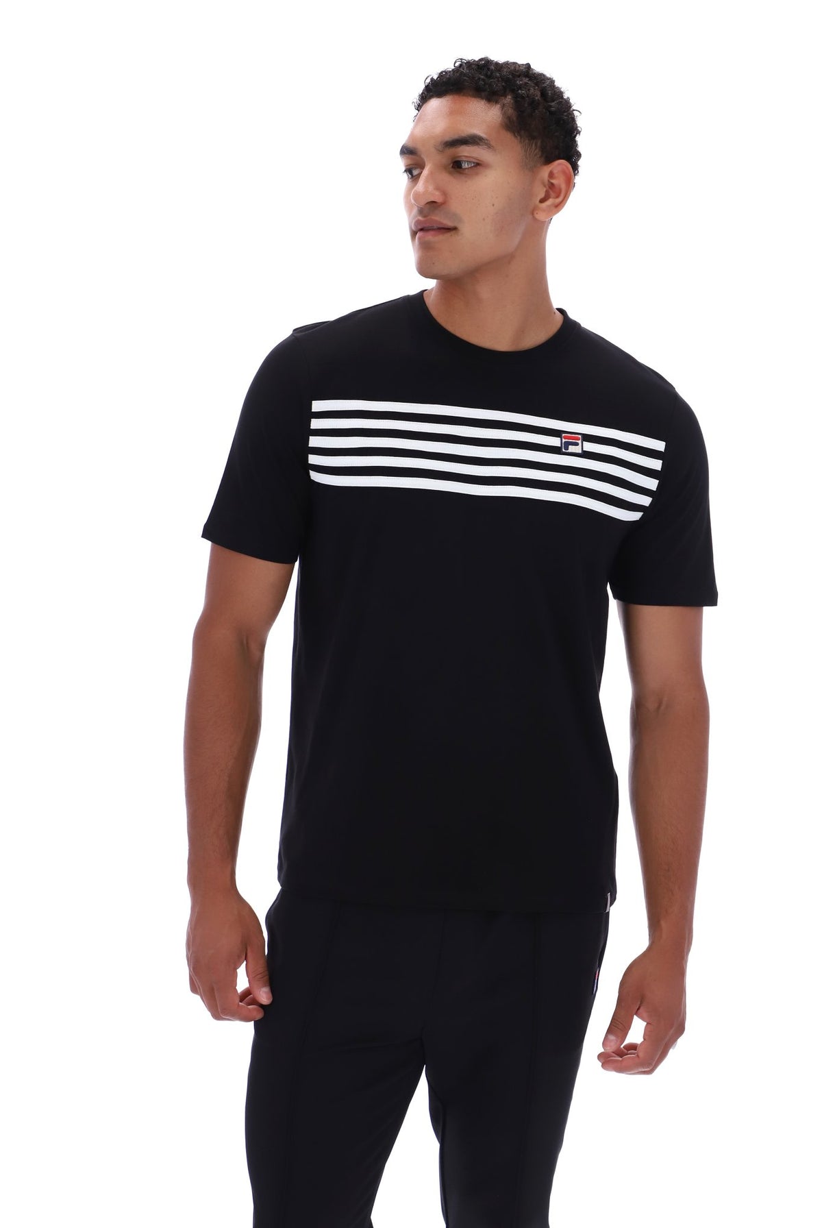 A man wearing a black short-sleeve t-shirt with a horizontal white stripe pattern across the chest and a small red and white FILA logo on the left chest, paired with black pants, against a plain white background.