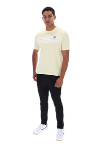A man modeling a pale yellow short-sleeve t-shirt with three horizontal white stripes across the chest and a small red and white logo on the left chest, paired with black pants and white sneakers, against a plain white background.