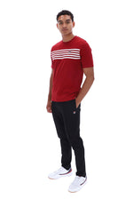 A man modeling a red short-sleeve t-shirt with three horizontal white stripes across the chest, paired with black pants and white sneakers, against a plain white background.