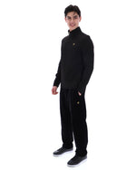 Man wearing a black jacket with a FILA gold logo, paired with matching bottoms, against a white background