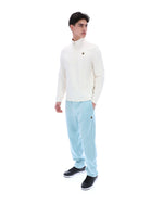 Man wearing a white sweater and light blue pants on a white background