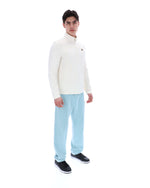Person wearing a white sweater and light blue pants on a white background