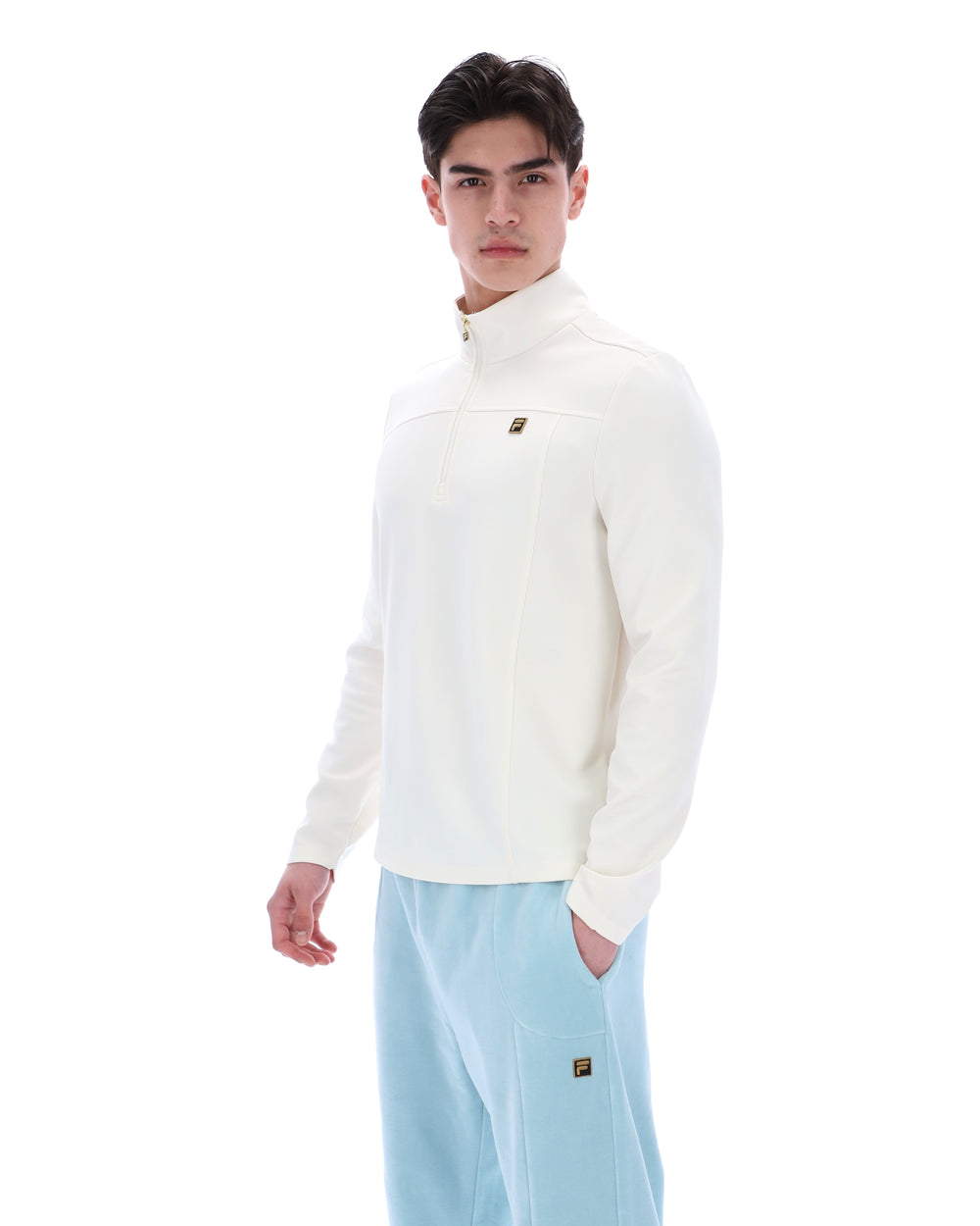 Person wearing a white quarter zip jumper and light blue pants on a white background