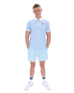 Man wearing a light blue checkered polo shirt and shorts set on a white background