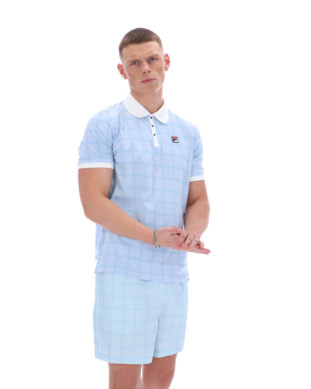 Man wearing a light blue checkered outfit with a white collar on a white background