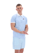 Man wearing a light blue checkered outfit with a white collar on a white background