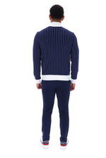 A man viewed from behind wearing a navy blue pinstriped sweater with white ribbed trim, navy pants, and white sneakers with red accents, set against a plain white background.