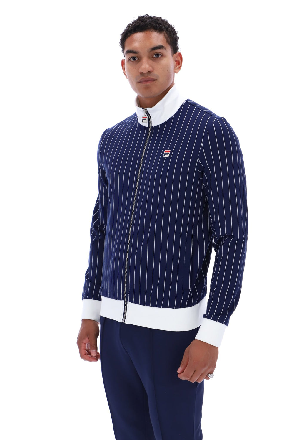 A man modeling a navy blue pinstriped zip-up jacket with white trim and a small red, white, and blue Filson logo on the chest, paired with navy pants, against a plain white background.