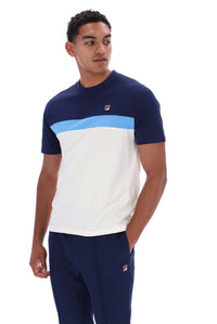 A man wearing a navy blue, white, and light blue color-blocked short-sleeve t-shirt with a small red and white Fila logo on the chest, paired with matching navy pants, against a plain white background.