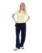 Woman wearing a yellow polo shirt and navy pants on a white background