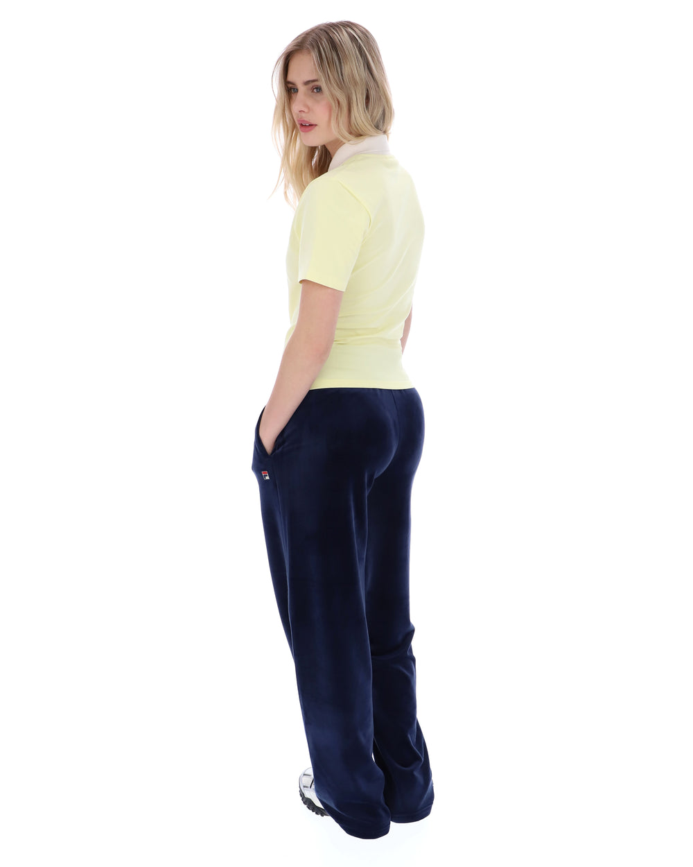 Woman wearing a yellow polo shirt and navy blue pants on a white background