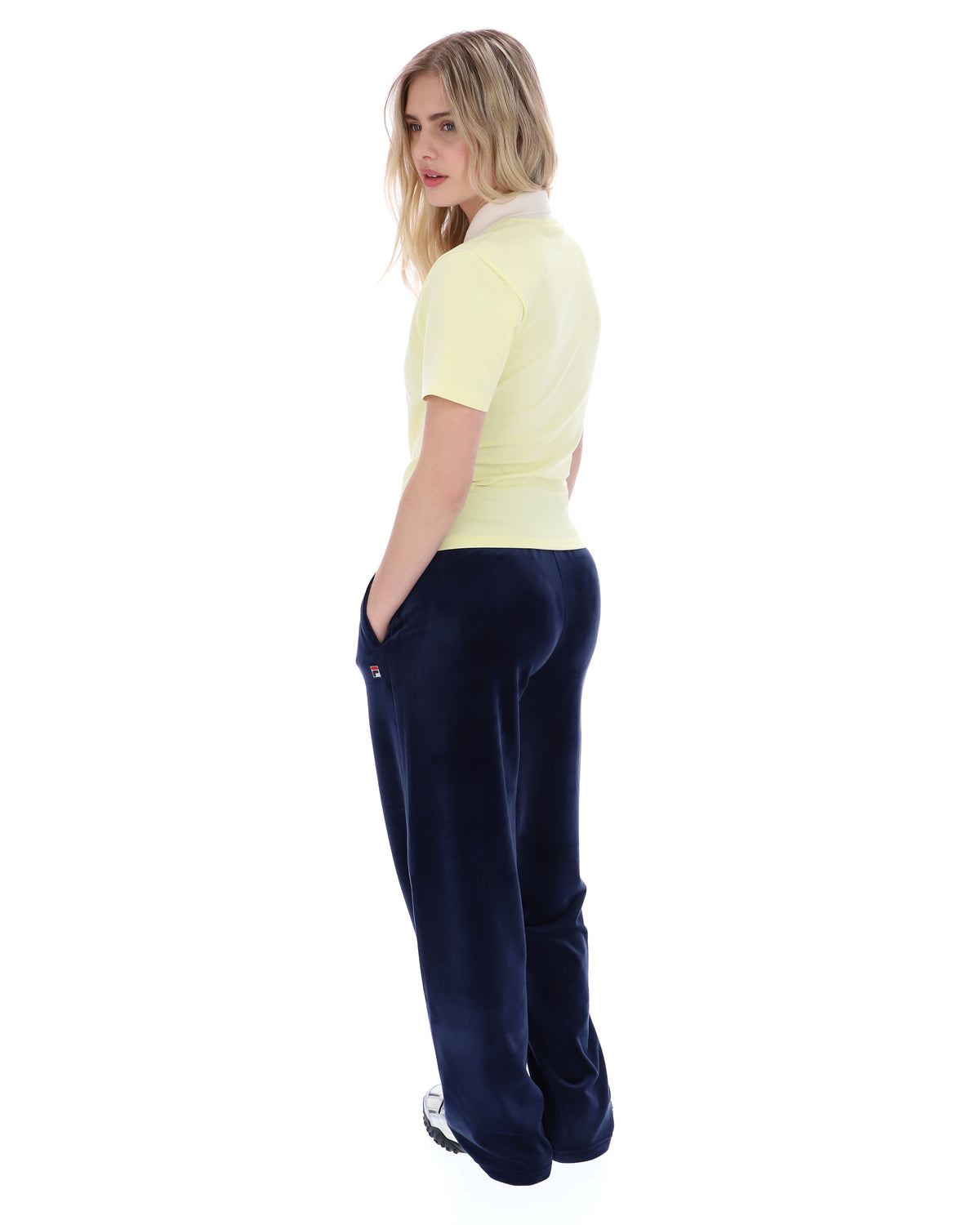 Woman wearing a yellow polo shirt and navy blue pants on a white background