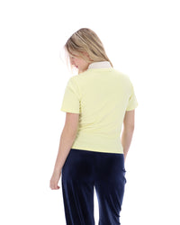 Woman wearing a light yellow polo shirt and navy pants on a white background