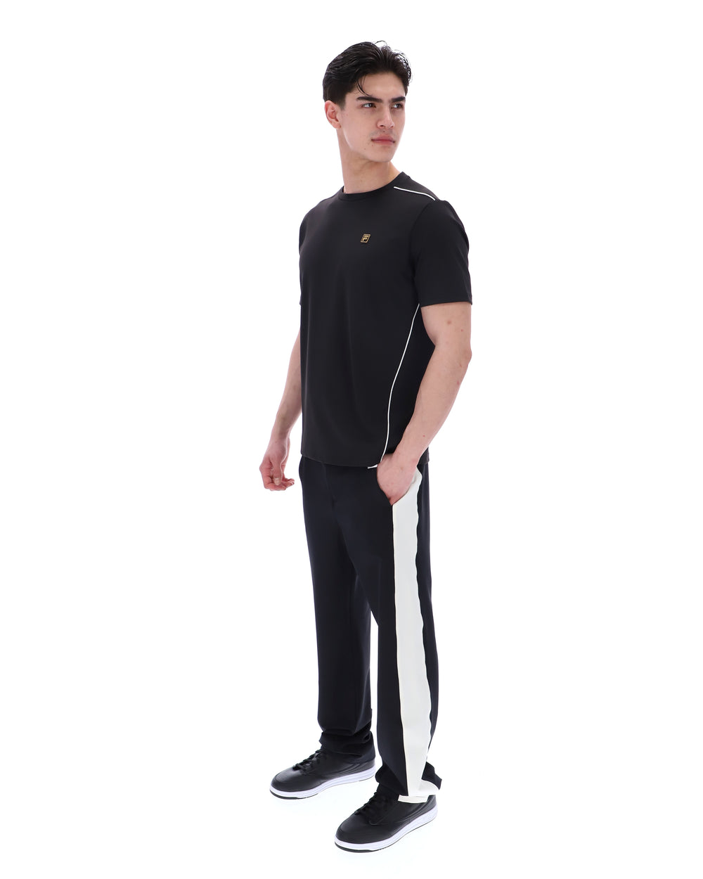 Man wearing a black t-shirt and black pants with white stripes on a white background