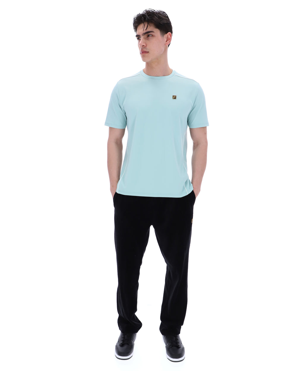 Man wearing a light blue t-shirt and black pants on a white background