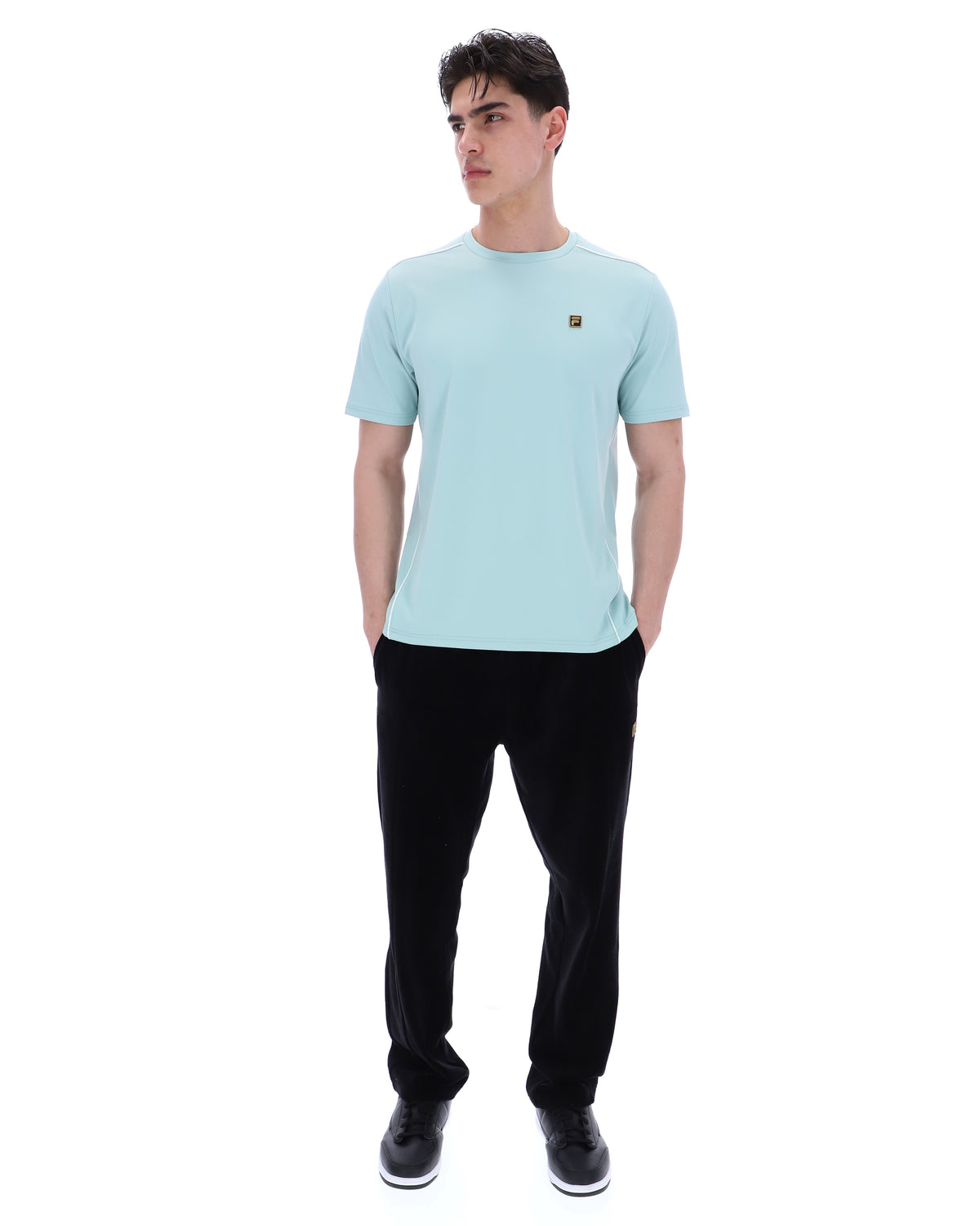 Man wearing a light blue t-shirt and black pants on a white background