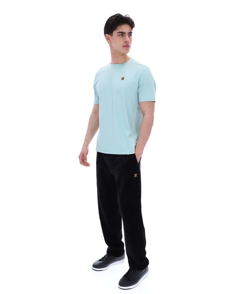 Person wearing a light blue t-shirt and black pants on a white background