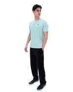 Person wearing a light blue t-shirt and black pants on a white background