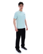 Man wearing a light blue t-shirt and black pants on a white background