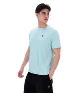 Man wearing a light blue t-shirt with a small logo on a white background