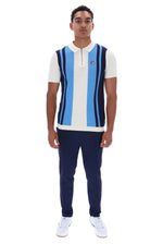 A man modeling a FILA short-sleeve polo knit vest with vertical light blue, white, and navy stripes, paired with navy pants and white sneakers, on a solid white background.