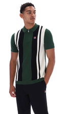 A man wearing a green, black, and white vertically striped knit polo vest with a half-zip collar, paired with black pants, against a plain white background.