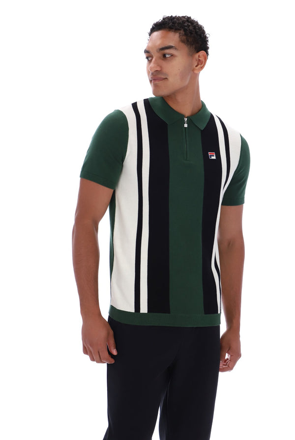 A man wearing a green, black, and white vertically striped knit polo shirt with a half-zip collar, posed against a solid white background.